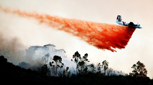 Avião joga água para tentar controlar incêndio florestal de grande proporção no subúrbio de San Marcos, California (EUA), nesta quinta-feira (15)