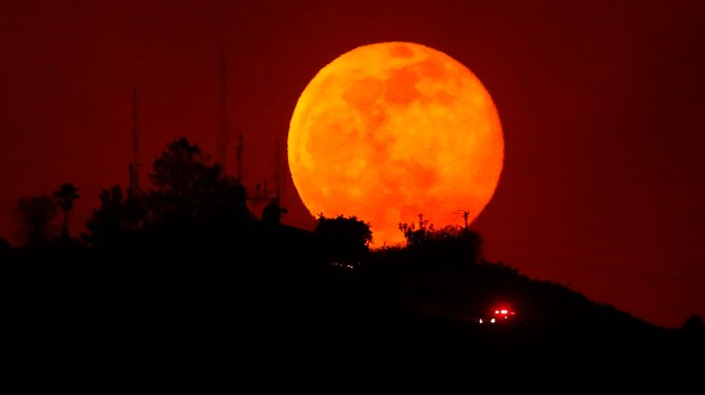 Veículo de emergência trafega durante a lua crescente ao longo de uma encosta queimada perto de San Marcos, na Califórnia