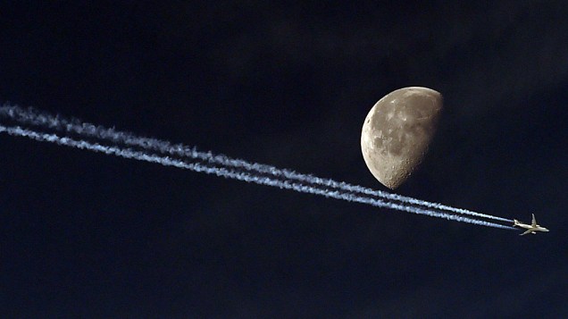 Avião a jato deixou um rastro de vapor ao passar em frente a lua em Argel, capital da Argélia