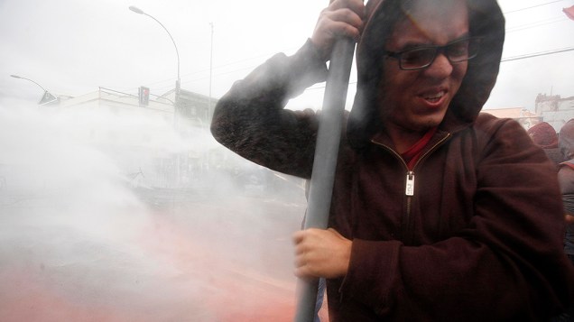 Manifestante tenta se proteger enquanto a polícia dispara um canhão de água durante confrontos em protesto contra as reformas educacionais propostas pelo governo em Valparaiso, no Chile