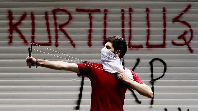 Manifestante usou um estilingue na frente de um graffiti com a palavra libertação, durante um protesto anti-governo em Istambul, na Turquia