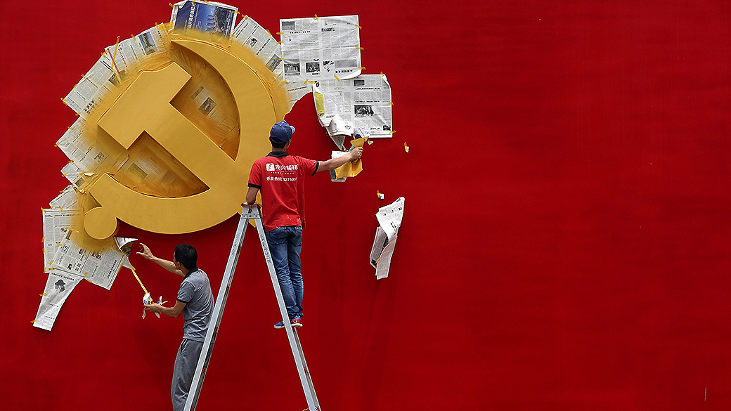 Trabalhadores pintam a bandeira do Partido Comunista Chinês sobre um muro do memorial da revolução Nanhu em Jiaxing, na China