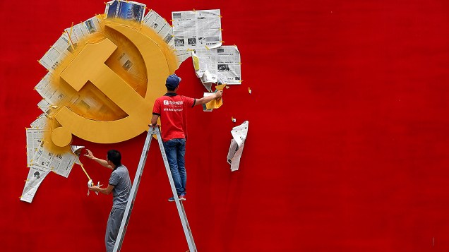 Trabalhadores pintaram a bandeira do Partido Comunista Chinês sobre um muro do memorial da revolução Nanhu em Jiaxing, na China