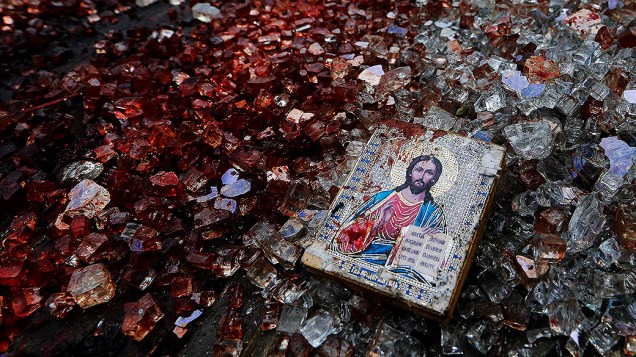 Ícone manchado de sangue com a imagem de Jesus visto sobre o vidro quebrado de um caminhão destruído perto do aeroporto de Donetsk, na Ucrânia