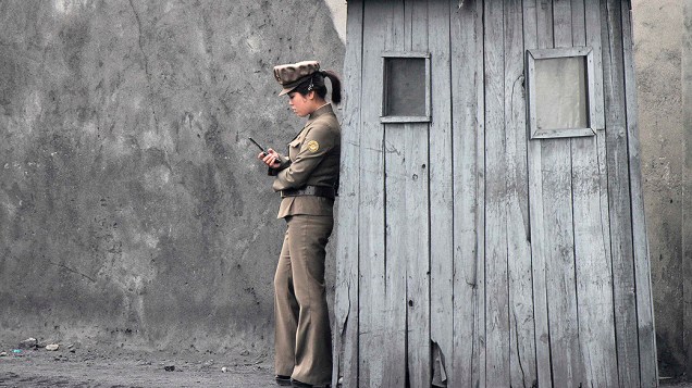 Soldado norte-coreana usa o seu telefone celular ao lado de um posto de vigilância às margens do rio Yalu, próximo à fronteira com a China
