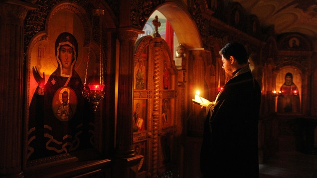 Sacerdote faz orações pelas vítimas da violência entre o exército nacional ucraniano e militantes separatistas pró-Rússia, na catedral Svyato-Preobrazhenski em Donetsk