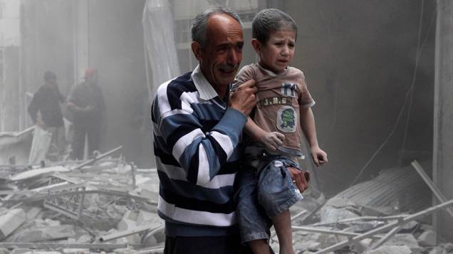 Na cidade de Alepo, homem segura garoto após um ataque aéreo por forças leais ao ditador sírio Bashar Assad