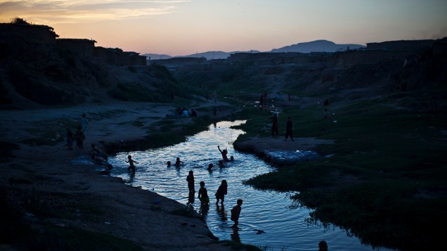 Refugiados afegãos tomam banho em um rio nos arredores de Islamabad, no Paquistão