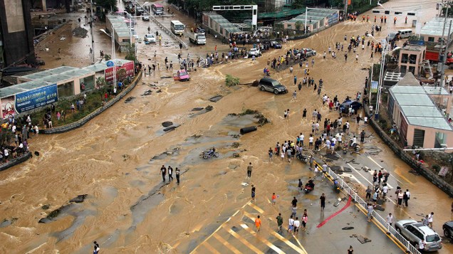Veículos tentam atravessar cruzamento inundado em Pingba, na província de Guizhou, na China