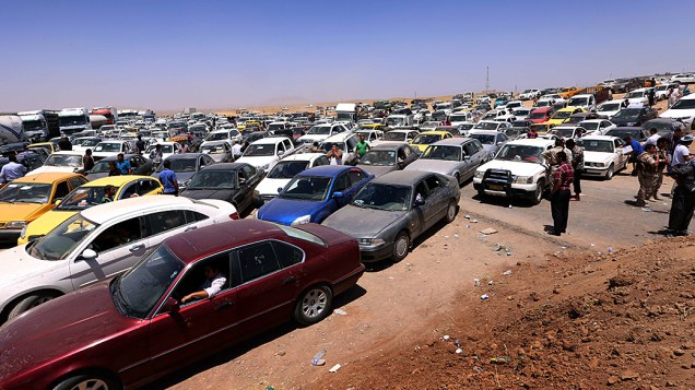Iraquianos esperam em seus veículos enquanto fogem da violência na província de Nínive em um posto de controle curdo no Aski Kalak, a oeste de Arbil, capital da região autônoma curda do norte do Iraque