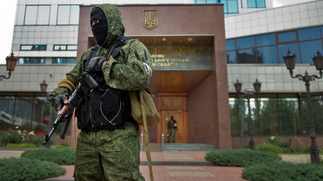Soldado pró-Rússia fica de guarda do lado de fora do Banco Nacional da Ucrânia após a apreensão do edifício em Donetsk, ao leste do país; A ação é uma tentativa de ganhar controle sobre seus ativos