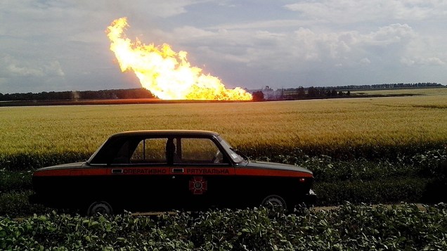 Imagem divulgada pelo Serviço de Emergência da Ucrânia mostra um carro da polícia estacionado próximo a um incêndio de um gasoduto na aldeia de Iskivtsi