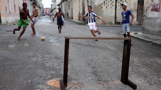 Grupo de adolescentes joga futebol em uma rua de Havana, em Cuba