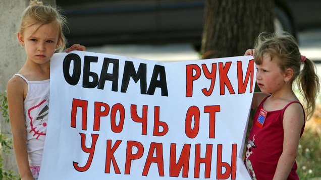 Em frente a embaixada da Ucrânia, crianças seguram um cartaz que diz Obama mãos fora da Ucrânia referindo-se ao presidente dos Estados Unidos durante um protesto contra ações das autoridades ocidentais em Kiev