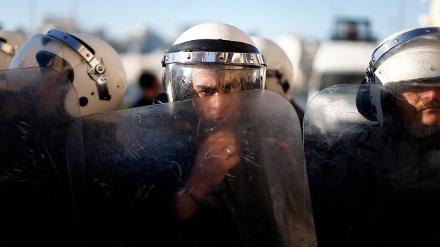 Policiais palestinos olham por trás de seus escudos, um grupo de manifestantes que protesta contra a cooperação entre a polícia palestina e israelense na busca por três jovens israelenses desaparecidos que supostamente foram sequestrados pelo grupo Hamas, em Ramallah, na Cisjordânia