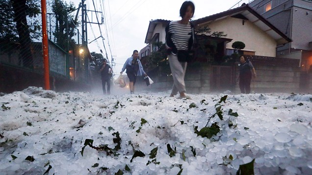 Pedestres andam por uma rua coberta de granizo após tempestade em uma área residencial a oeste de Tóquio, no Japão