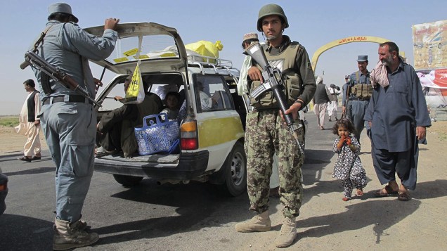 Oficiais da segurança afegã inspecionam os veículos de refugiados dos quatro distritos de Helmand, em sua chegada em Lashkar Gah, a capital da província, no Afeganistão; Confrontos entre talibãs e as forças de segurança nacional nestes locais já deixaram quase 160 mortos e milhares de desabrigados