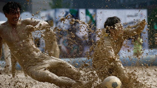 Disputa de bola em partida de um torneio de futebol no pântano, em Pequim, China