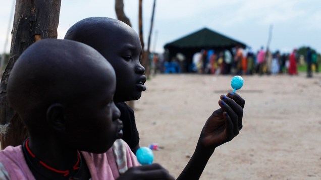 Crianças comem doces para esperar a distribuição de alimentos em Minkaman, no Sudão; De acordo com a Organização Internacional para as Migrações, cerca de 94 mil pessoas buscaram refúgio na região após o início dos conflitos nos países vizinhos