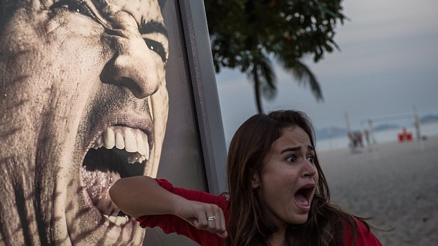 Turista faz brincadeira com uma imagem publicitária de Luis Suárez na praia de Copacabana, no Rio de Janeiro. O atacante uruguaio foi punido pela Fifa após morder o jogador italiano Giorgio Chiellini em partida da Copa do Mundo
