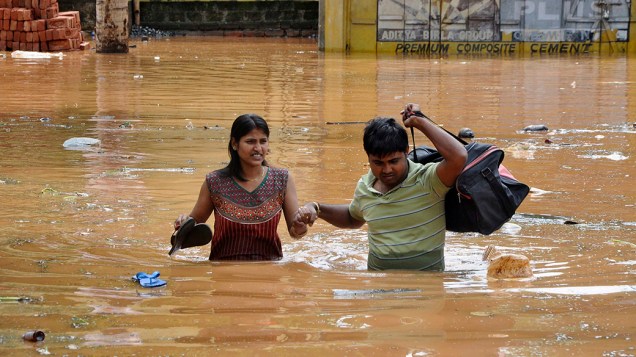 Centenas de pessoas estão desabrigadas devido as fortes chuvas no norte da Índia; Na imagem, moradores percorrem uma estrada inundada na tentativa de encontrar um local mais seguro após tempestade, na cidade de Guwahati