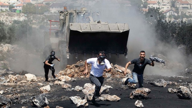 Manifestantes correm de uma escavadeira militar israelense durante confrontos com tropas nacionais após protesto contra o assentamento judaico, perto da cidade de Qadomem, na Cisjordânia