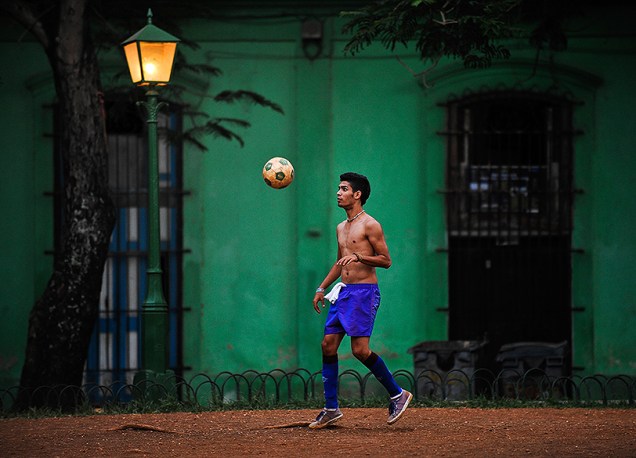 Jovem joga futebol em uma rua de Havana, em Cuba