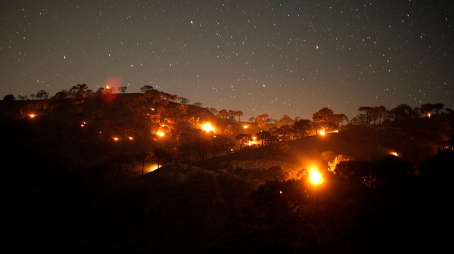 Pequenos incêndios florestais são retratados entre pinheiros durante a noite, na Serra de Tejeda, próximo à Málaga, sul da Espanha
