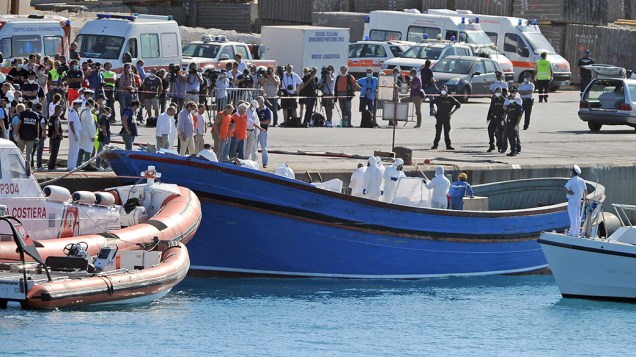 Bombeiros e policiais evacuam corpos de migrantes de um barco no porto de Pozzallo, Sicília, dois dias depois de uma operação de resgate na costa italiana