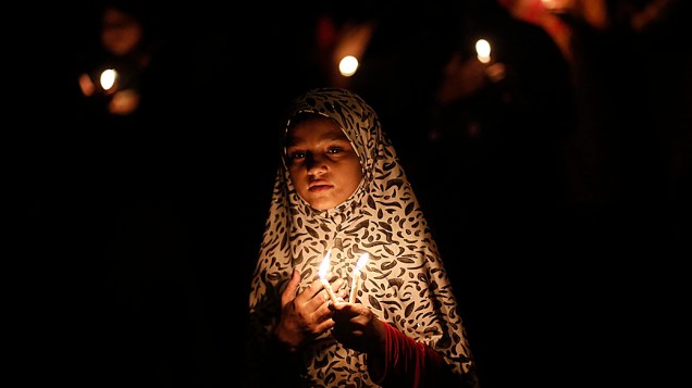 Menina muçulmana xiita participa de um protesto à luz de velas contra o conflito no Iraque, em Nova Delhi, na Índia