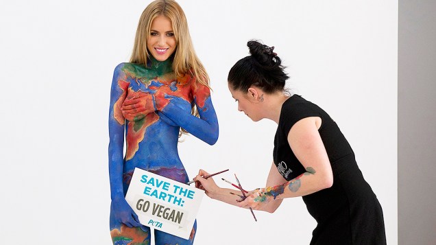 A modelo Renee Somerfield recebe retoques em uma pintura corporal enquanto segura um cartaz que diz: "Salve a Terra, torne-se Vegan" para um novo anúncio da ONG PETA (Pessoas pelo Tratamento Ético dos Animais), em Sydney, na Austrália