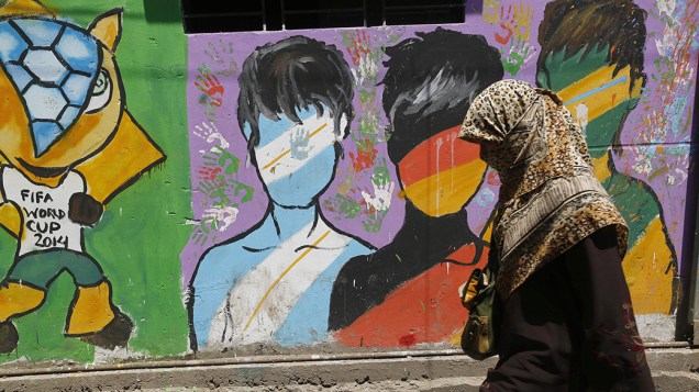 Em Bangladesh, mulher passa por uma parede pintada em homenagem a Copa do Mundo de Futebol, na cidade de Dhaka; O mundial termina neste domingo (13)