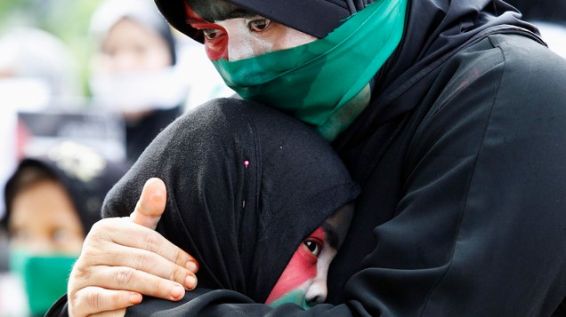 Mulher com as cores da bandeira palestina pintada no rosto, chora enquanto abraça o filho durante um comício realizado em frente a embaixada israelense em Taguig, nas Filipinas. A manifestação pediu às Nações Unidas para ajudar a resolver o conflito entre Israel e militantes palestinos na Faixa de Gaza