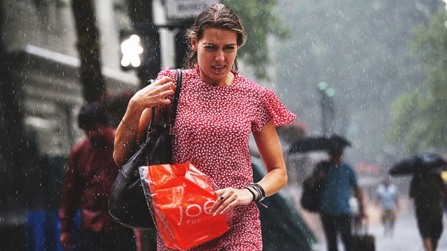 Mulher atravessa a Quinta Avenida, em Manhattan durante uma tempestade