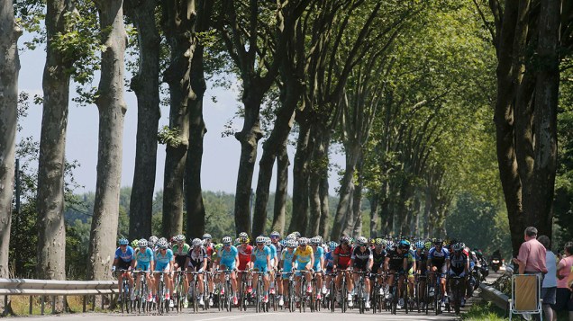 Chega ao décimo segundo estágio a maratona anual da categoria de ciclismo, a Tour de France. Na imagem, atletas passam por uma estrada arborizada entre as cidades de Bourg-en-Bresse e Saint Etienne, na região central no país