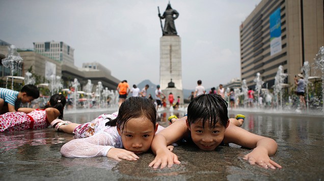 Crianças brincam em uma fonte para se refrescar em um dia quente de verão em frente à estátua do General sul-coreano Lee Soon-shin em Seul 