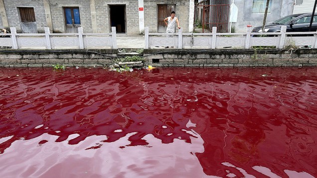 Imagem do dia 24 de julho divulgada hoje, mostra um homem olhando para um tingido de vermelho em Cangnan na província de Zhejiang na China. Segundo autoridades locais, baldes de tinta foram deixados próximos à margem, o material porém não contém substâncias prejudiciais à saúde