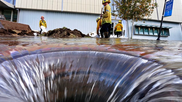 Bombeiros trabalham perto de um dreno aberto no campus da Universidade de Los Angeles, que ficou inundado após ruptura de uma adutora 