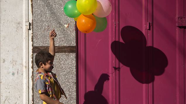 Menino palestino brinca com balões enquanto famílias deixam suas casas no bairro de Shejaiya na Cidade de Gaza com medo de ataques israelenses, depois que facções palestinas se recusaram a estender o cessar-fogo de 72 horas com Israel