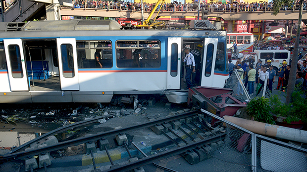 Policiais filipinos e membros dos serviços de resgate, inspecionam área após o descarrilamento de trem, em Manila
