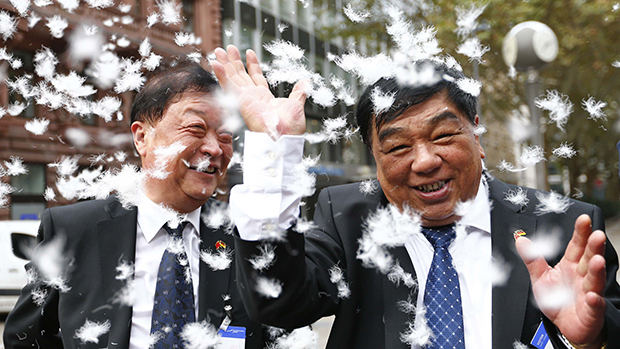 Executivos da empresa chinesa de processamento e manufatura Snowbird AG jogam plumas para o ar celebrando o lançamento da empresa na bolsa de valores em Frankfurt, na Alemanha. À direita, Yan Changzai (CEO), ao lado de Qiu Duoxiang (COO)