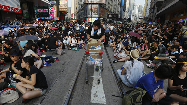 Estudante passa distribuindo alimentos e água para milhares de jovens que ocupam um via principal do distrito de compras em Hong Kong, em protesto exigindo democracia no território chinês