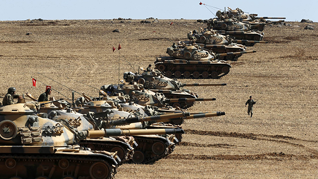 Tanques do exército turco se posicionam na fronteira da Turquia com a Síria, perto da cidade de Suruç. Combatentes curdos desarmados prometeram manter seus esforços cada vez mais desesperados de defender a cidade síria de Kobani do Estado Islâmico