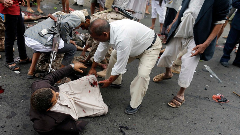 Rebeldes xiitas ajudam homem ferido após ataque suicida próximo a uma mesquita em Sanaa, capital do Iêmen. Ao menos 32 pessoas foram mortas no atentado