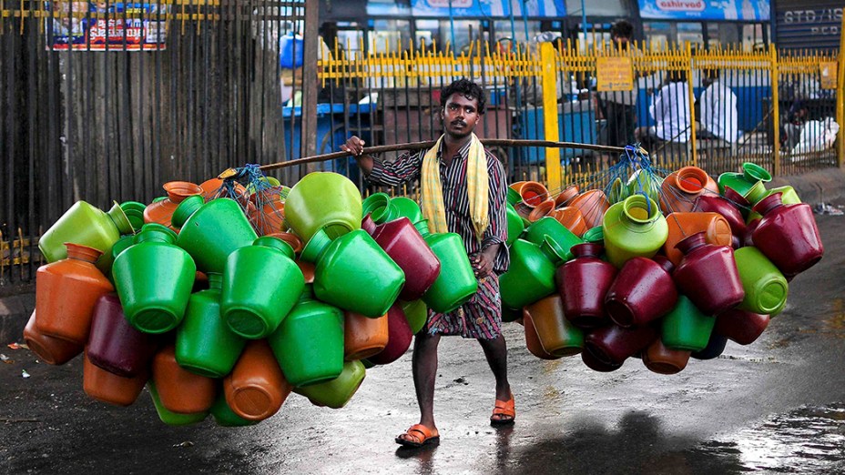 Vendedor carrega jarros de água em um mercado na cidade indiana de Bangalore