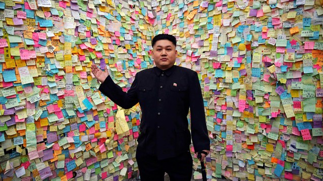 O músico Howard, 35, sósia do ditador da Coreia do Norte, Kim Jong-un, na frente de um mural com mensagens de apoio ao movimento pró-democracia no centro de Hong Kong, na China. Manifestantes ocupam avenidas da cidade para exigir eleições diretas