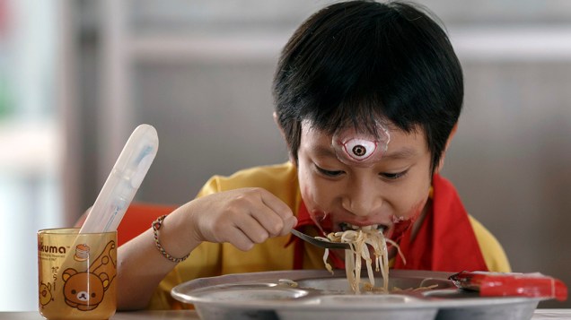 Menino fantasiado para o Halloween come merenda escolar em Bangcoc, na Tailândia