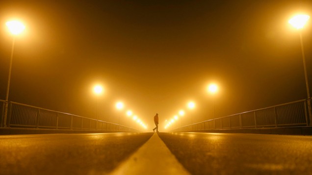 Homem fotografado durante a madrugada em uma rua de Zenica, na Bósnia e Herzegovina, em meio à densa neblina