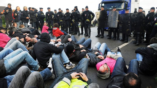 Funcionários de um matadouro deitam no chão durante um protesto contra corte de empregos em Lampaul-Guimiliau, França