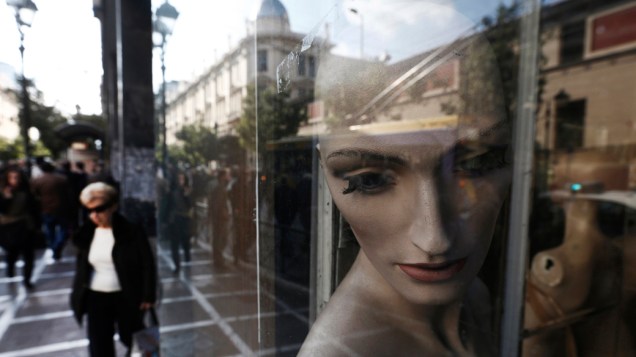 Mulher passa por comércio fechado o centro de Atenas, na Grécia